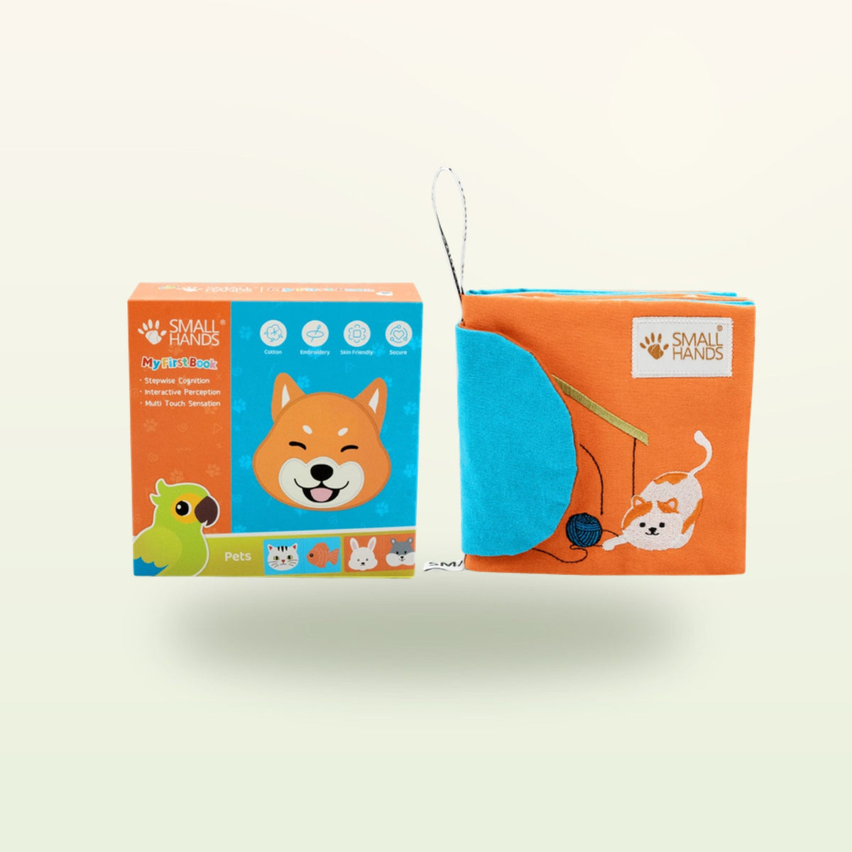 Small Hands Mascotas libro sensorial Montessori – embalaje con libro, perro Shiba y gato jugando sobre fondo suave de color crema – a partir de 0 meses