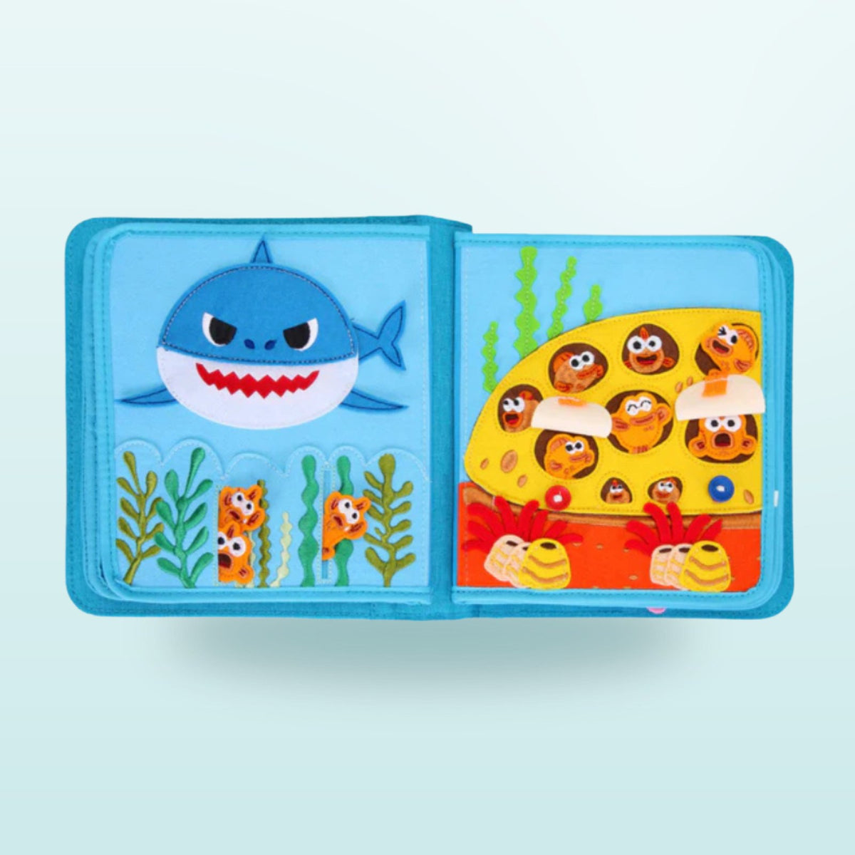 Doble página del quiet book Baby Shark con casa submarina y solapas escondidas para buscar sobre fondo suave de mar – a partir de 3 años