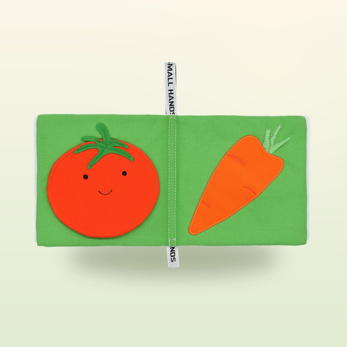 Small Hands Gemüse Montessori Stoffbuch Doppelseite mit Tomate und Karotte auf sanftem Wiesengrün-Hintergrund – ab 1 Jahr