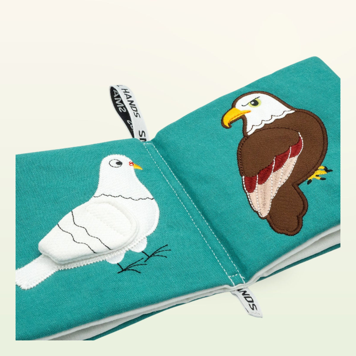 Small Hands Birds Montessori cloth book open – white dove and eagle at an angle on a soft cream background – from 0 months