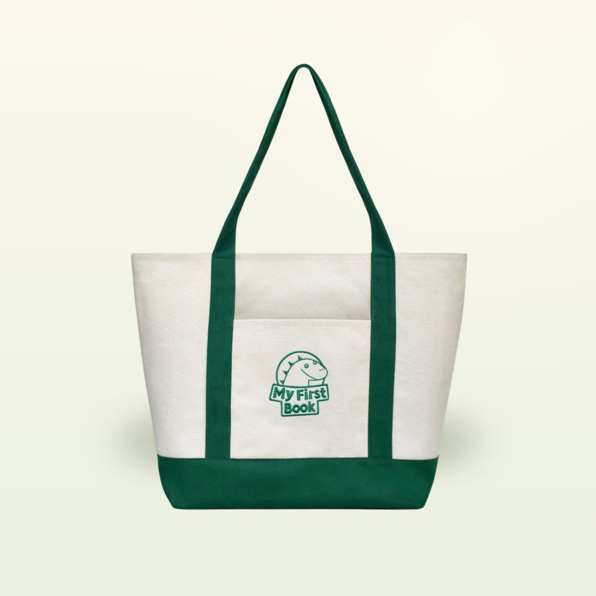 My First Book Tragetasche – cremefarbene Stofftasche mit grünen Henkeln, Vorderansicht auf sanftem Creme-Hintergrund