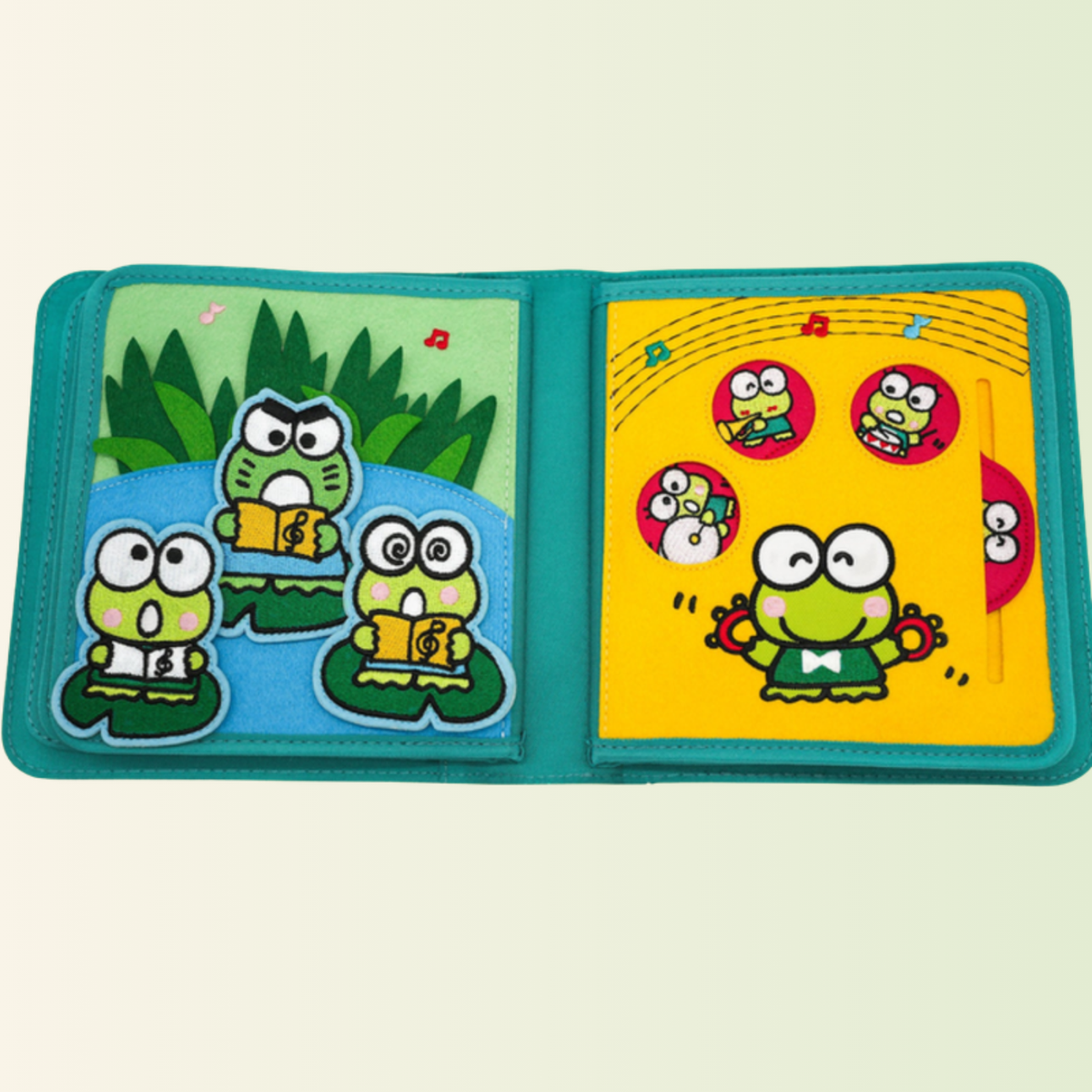 Quiet book Keroppi – concierto de ranas con pieza deslizante, recortado sobre fondo suave de pradera
